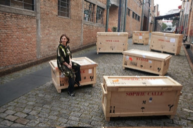 
	Artist Sophie Calle with boxes holding her pieces
	Photo: Everton Ballardin
